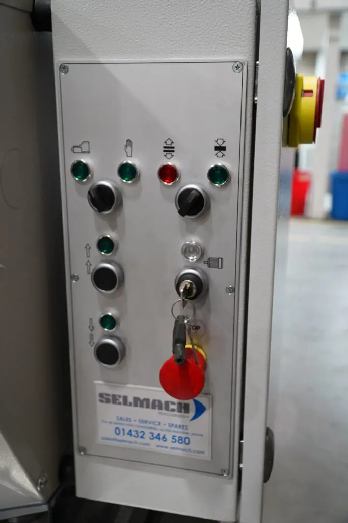 Industrial control panel for a Selmach machine featuring various buttons, indicator lights, a keyed ignition, and a red emergency stop button