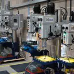 Line-up of Meyer metalworking machinery including pillar drills, with some other brand belt grinders in the background, arranged in a bright showroom with a clean white background."