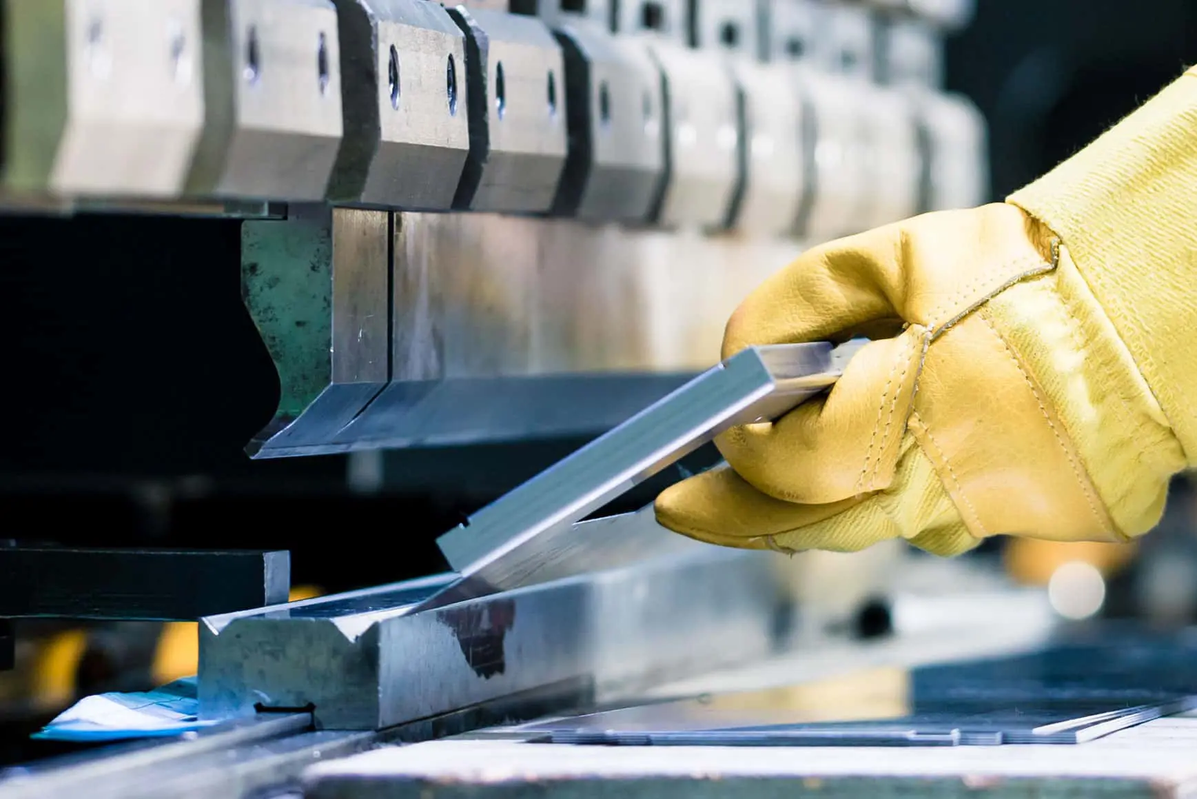 The-advantages-of-slowing-down-the-bending-process-on-a-pressbrake Image of gloved hands holding a piece of metal on a pressbrake