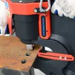 Close up image of someone punching holes into a steel beam