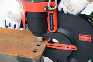 Close up image of someone punching holes into a steel beam