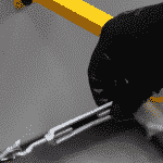 Close up of a hand turning the wire tension on a rolling machine