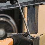 Close up of hands putting a piece of metal up to press brake tooling to fold