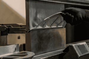 Image of a hand holding a piece of metal to be folded on a press brake