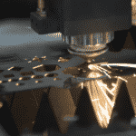Close up of Laser Cutting head cutting intricate sections on a metal sheet