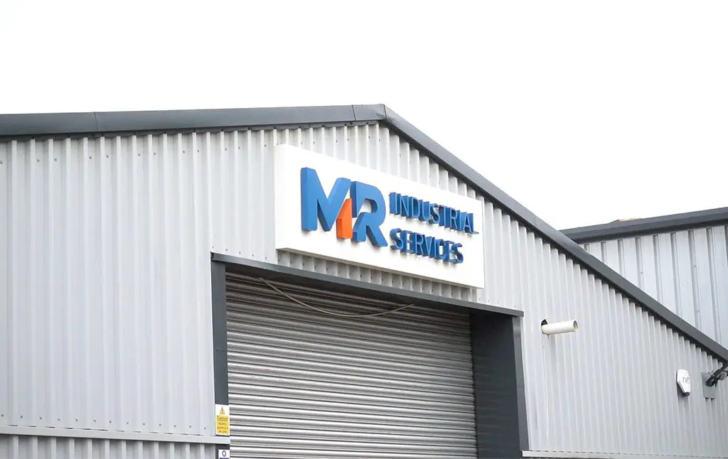 MR Industrial Services Logo on a pitched roof steel building, with a roller track door