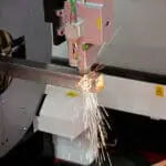 A close-up shot of a Raytools Laser Head cutting on a Tube Laser Cutter