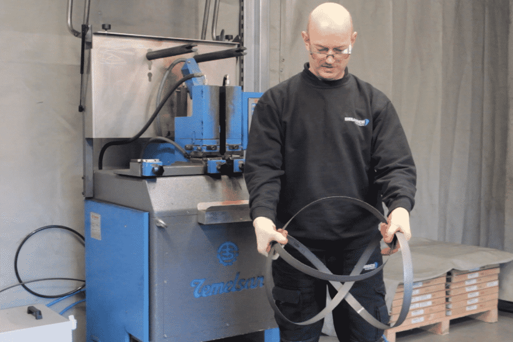 A technician demonstrating how to uncoil a bandsaw blade safely