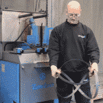 A technician demonstrating how to uncoil a bandsaw blade safely