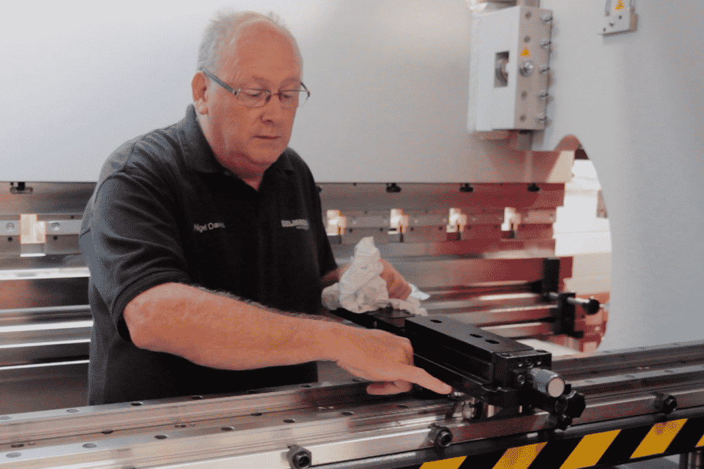 Image of a Selmach engineer inside the press brake conducting general maintenance on the backgauge